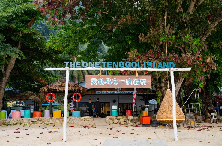 The One Tenggol Island Resort beach entrance arch with colourful buckets and a hanging rattan chair